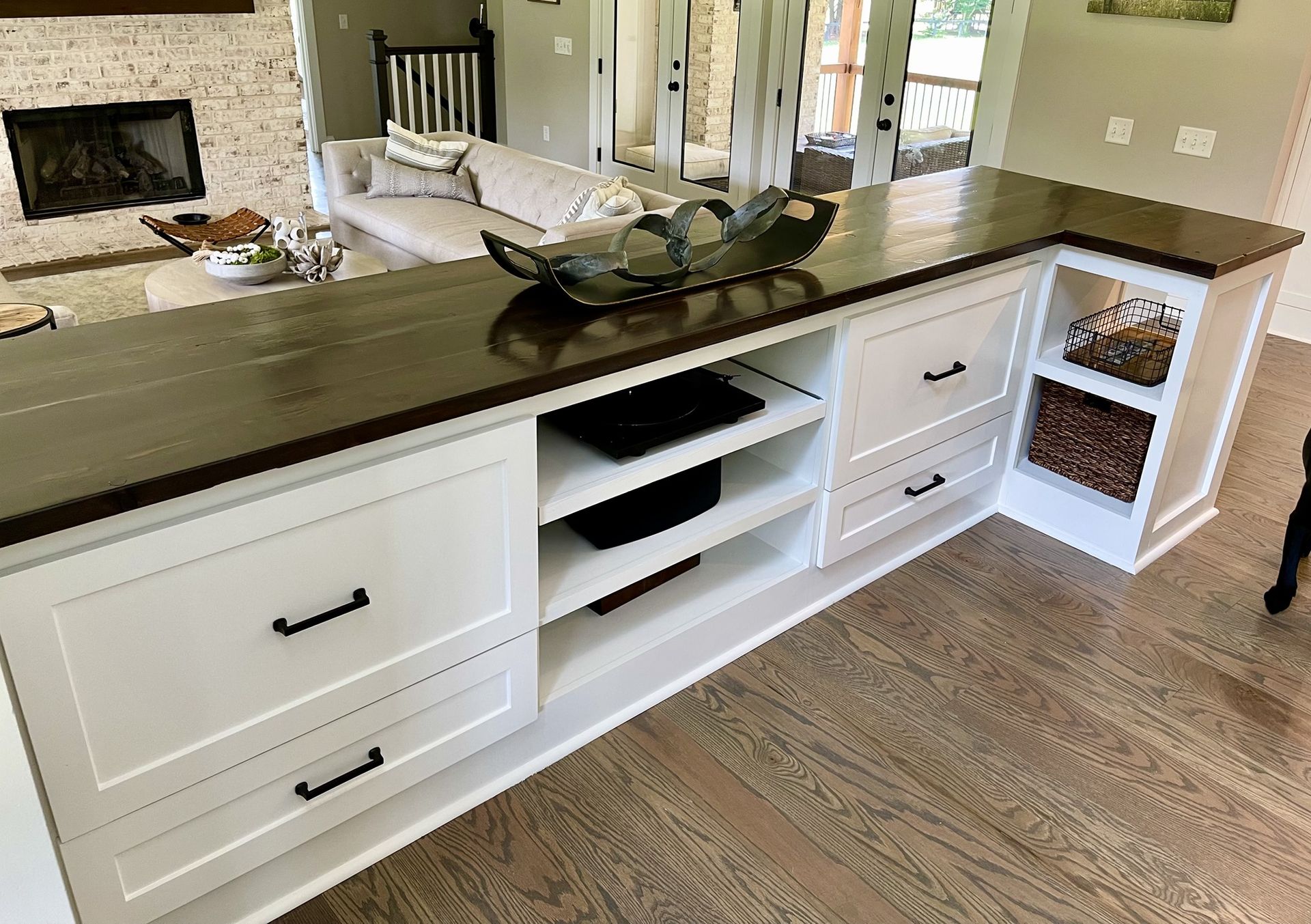 White built-in cabinet with dark wood top in a living room, with open shelves and drawers