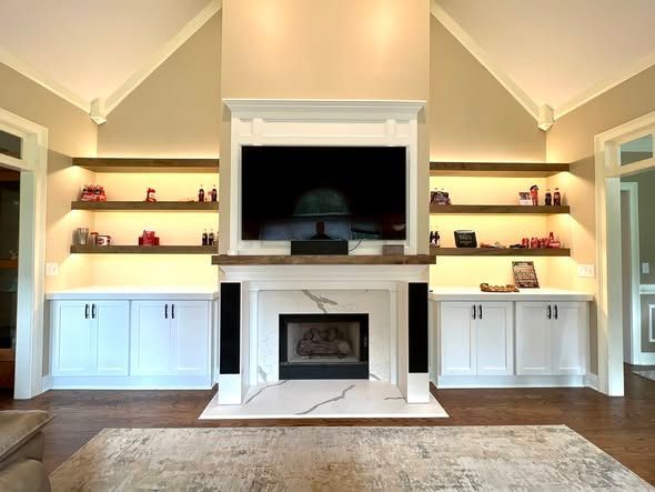 Elegant living room with built-in shelving, a white fireplace, and a mounted TV centered on the wall