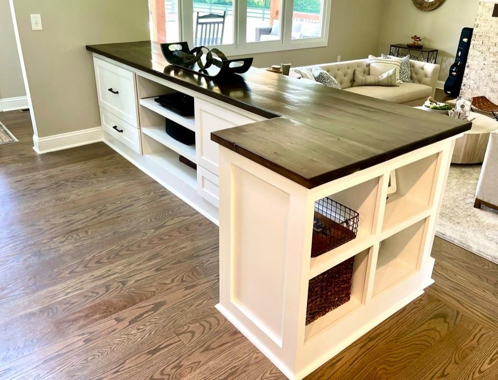 Kitchen island with white cabinets and dark wood top in a bright open room