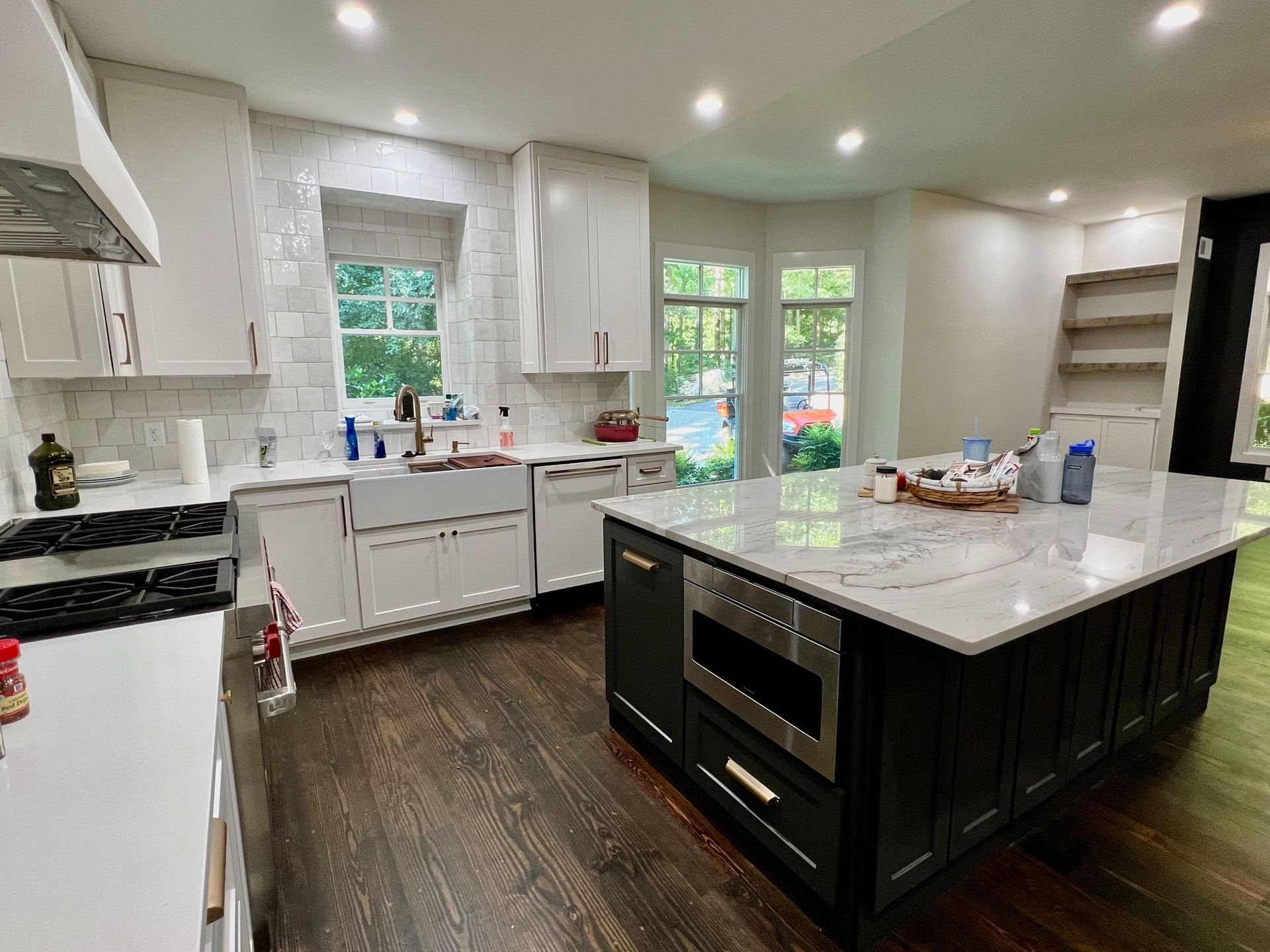Bright white kitchen with dark island, stainless stove, and sunlight through windows