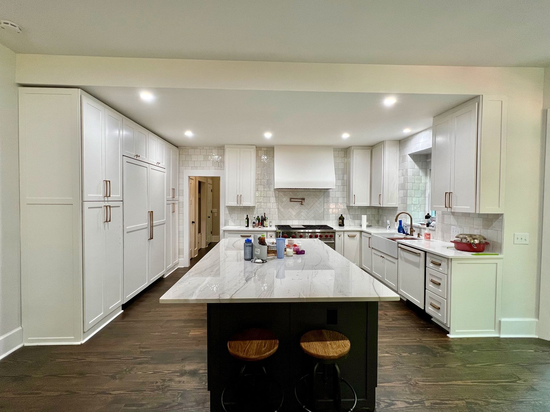 Bright modern kitchen with white cabinets, large island, and dark wood floors