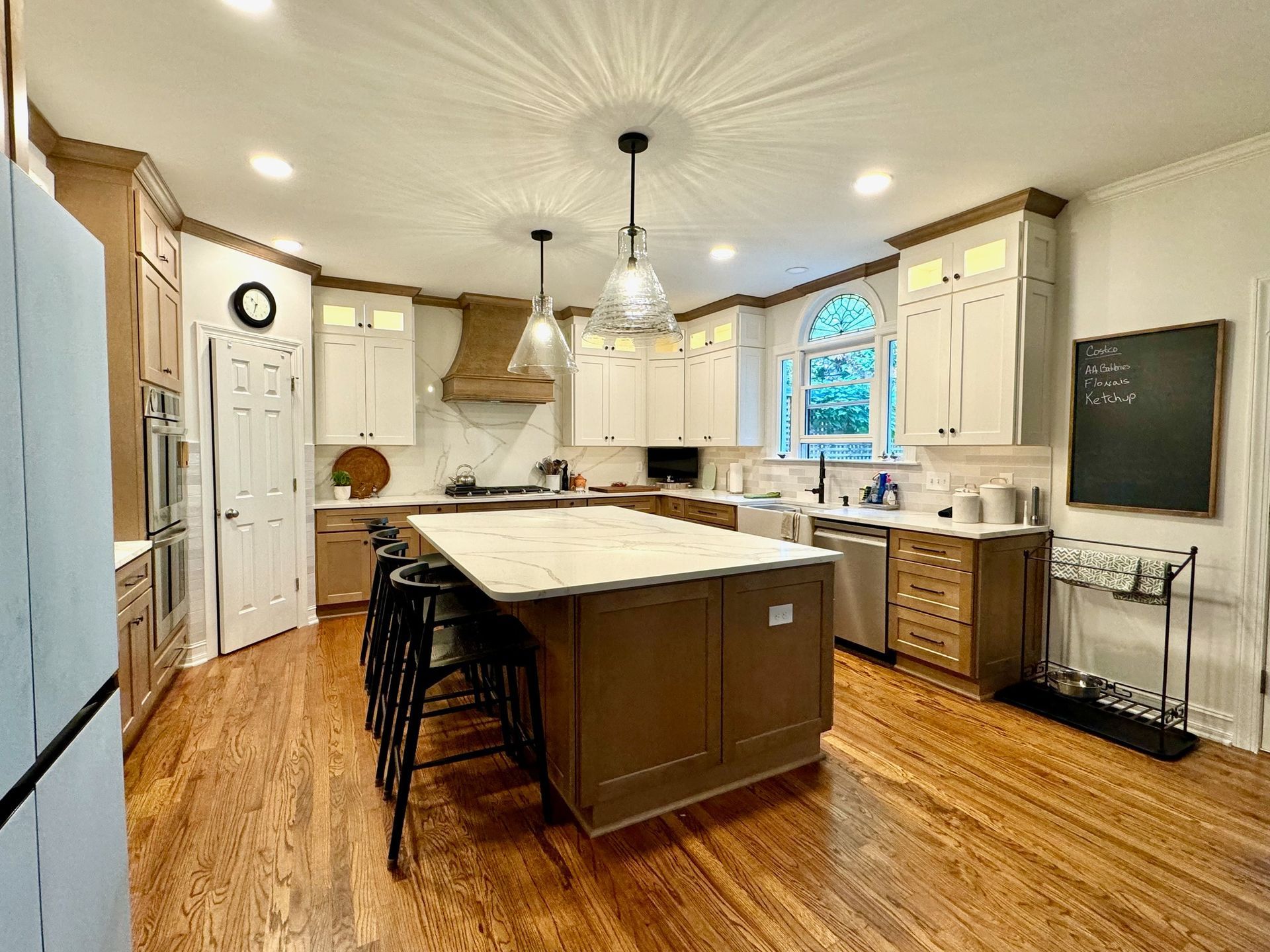 Bright kitchen with central island, white cabinets, wood floors, and a window over the sink