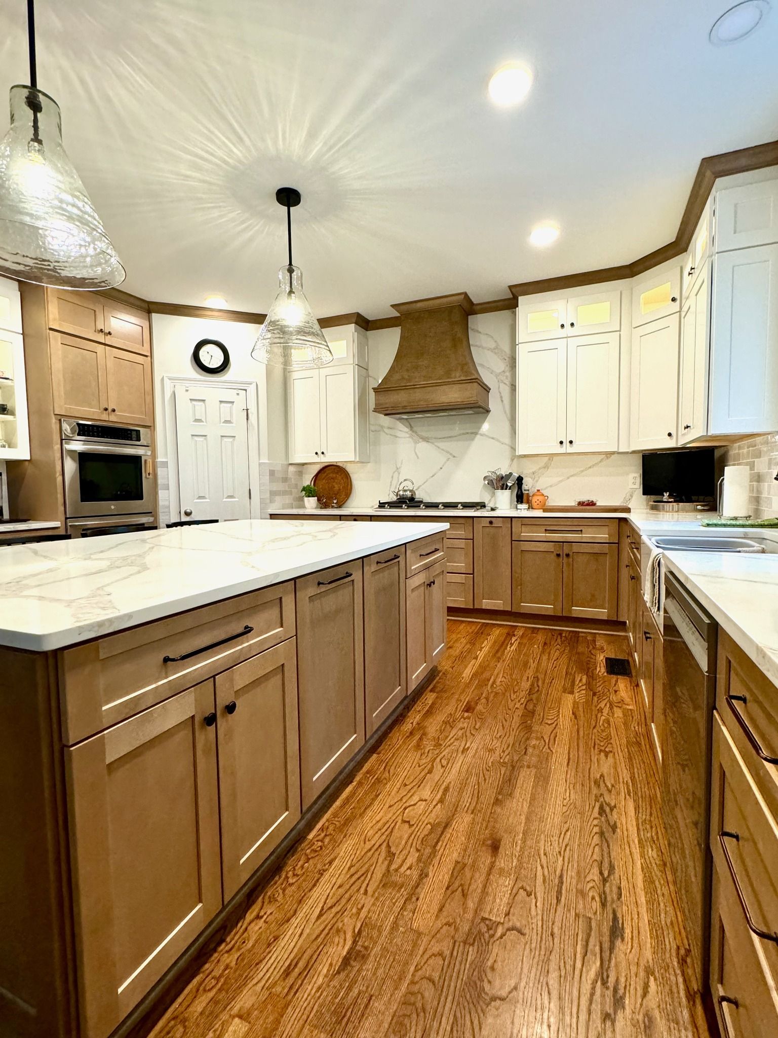 Bright kitchen with white cabinets, wood floors, central island, and stainless appliances.