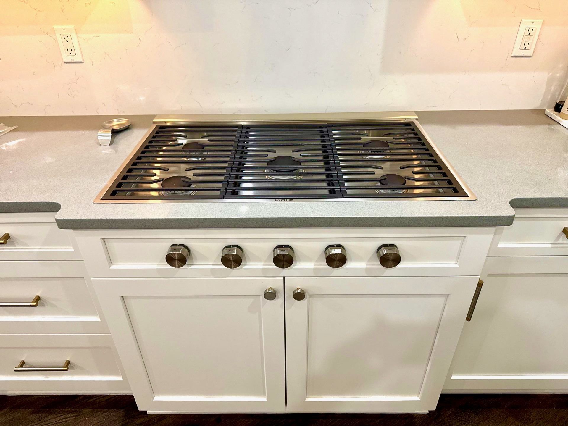 White kitchen island with built-in gas cooktop and silver countertop knobs