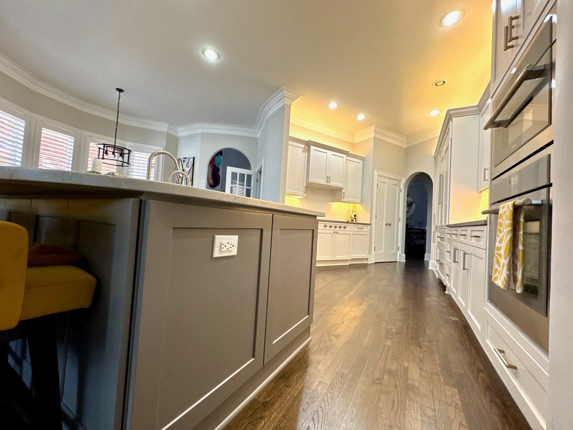 Bright modern kitchen with gray island, white cabinets, and built-in oven.