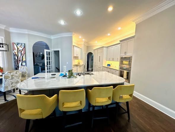 Bright modern kitchen with white island, yellow stools, and dark wood floors