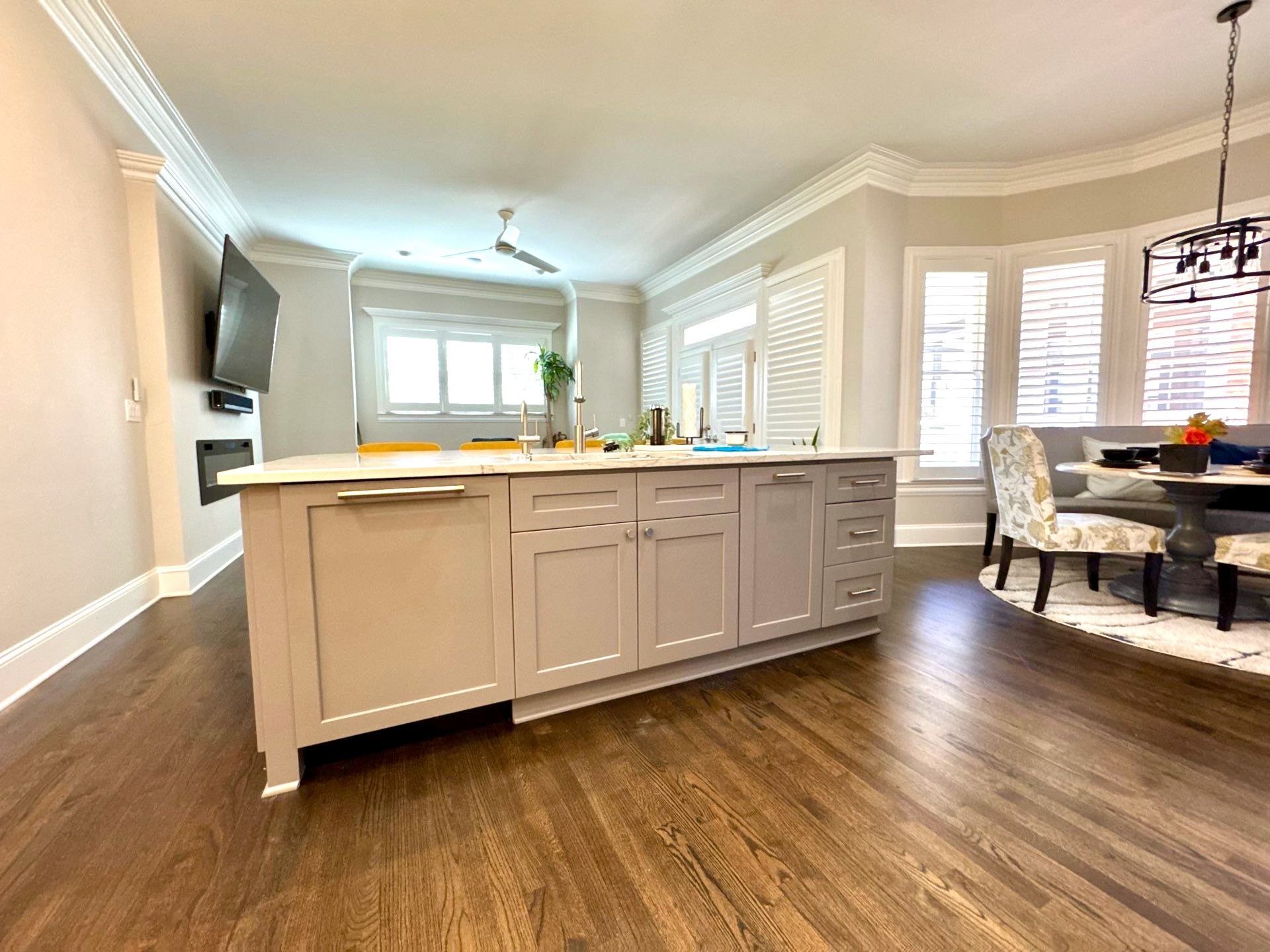 Bright open kitchen with beige island, wood floors, and dining area by large windows
