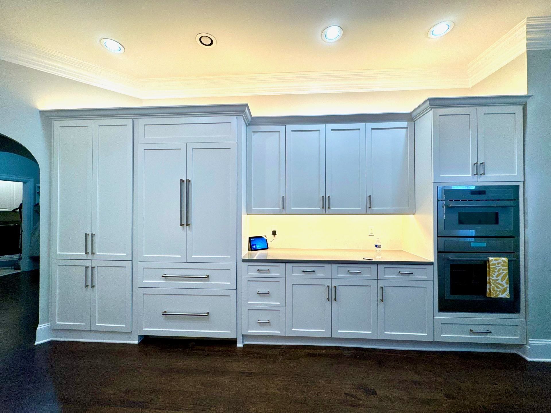 Modern white kitchen with built-in cabinets, marble backsplash, and stainless steel oven.