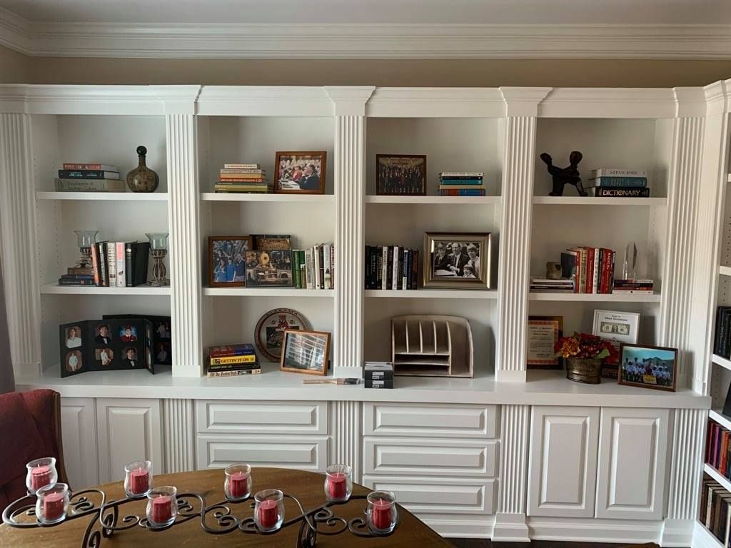 Built-in living room shelves with books, decor, and candles above white cabinetry