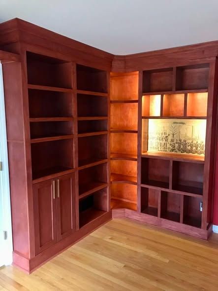 Corner wooden built-in shelving and cabinets in a room with hardwood floors.