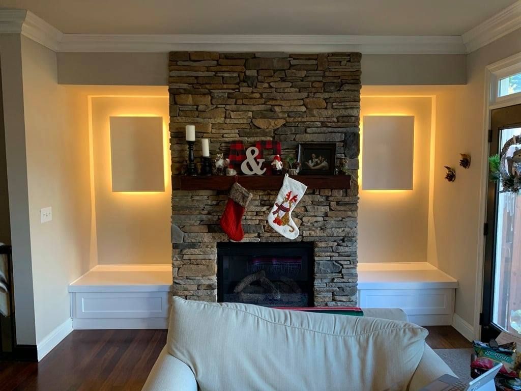 Living room fireplace with stone surround, lit wall niches, and Christmas stockings on the mantle
