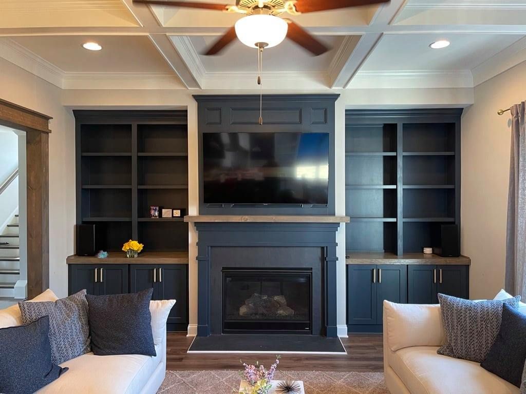 Living room with dark built-ins, a central fireplace, wall-mounted TV, and beige sofas