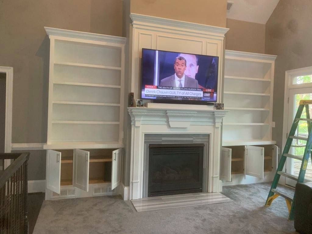Living room with built-in shelves, a fireplace, and a TV mounted above the mantel.