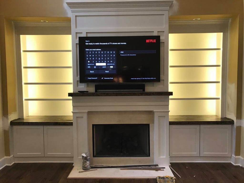 Modern living room with a white fireplace, built-in shelves, and a TV above it