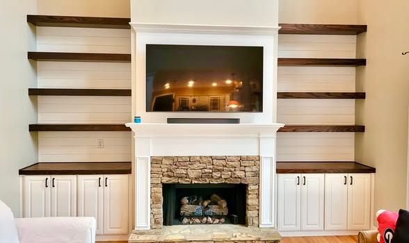 Living room fireplace with built-in shelves, white cabinetry, and dark wood accents