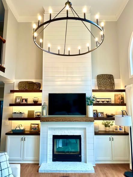 Bright living room with a fireplace, built-in shelves, TV, and large black circular chandelier