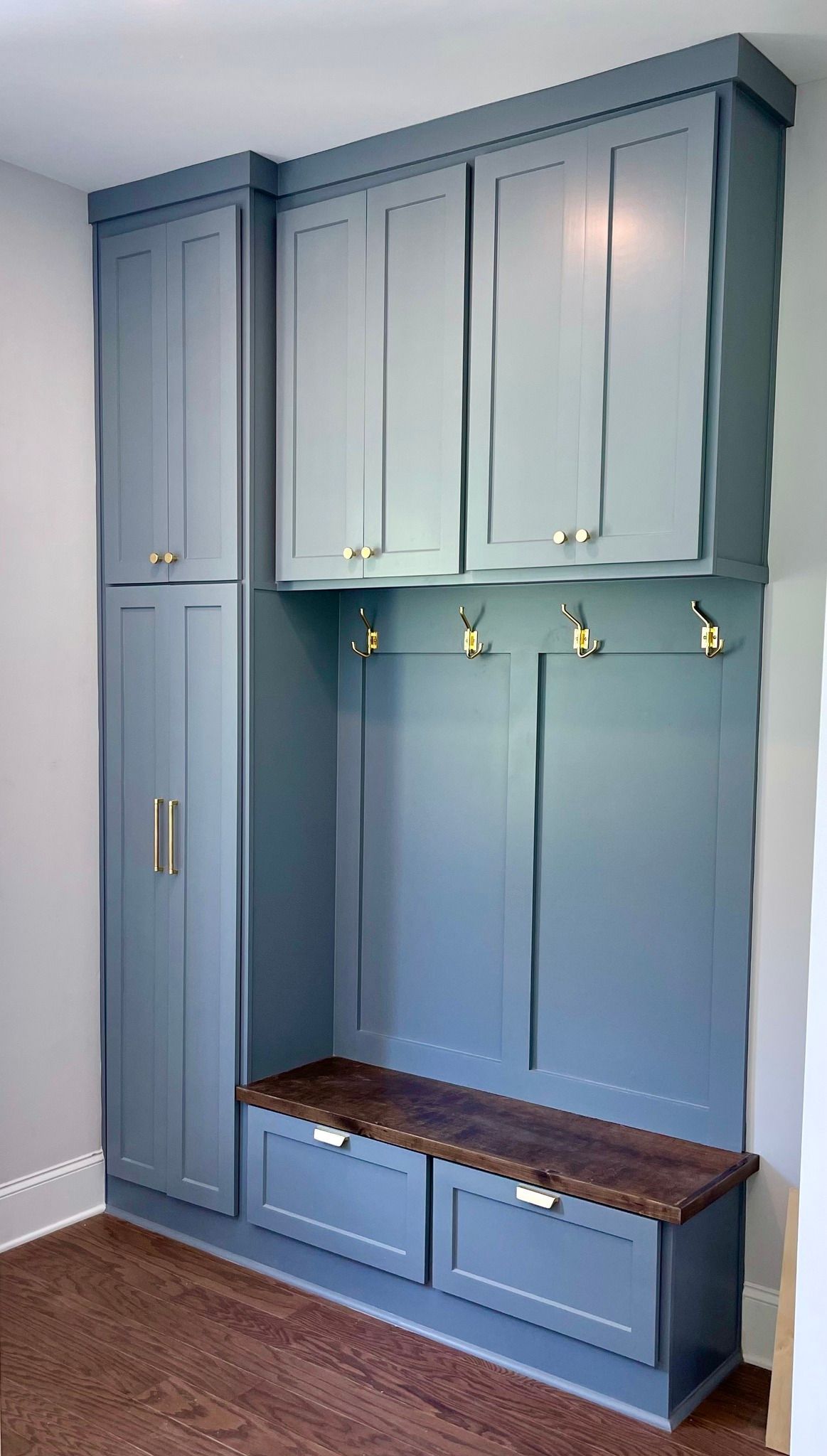 Blue built-in mudroom cabinet with bench, hooks, drawers, and tall storage