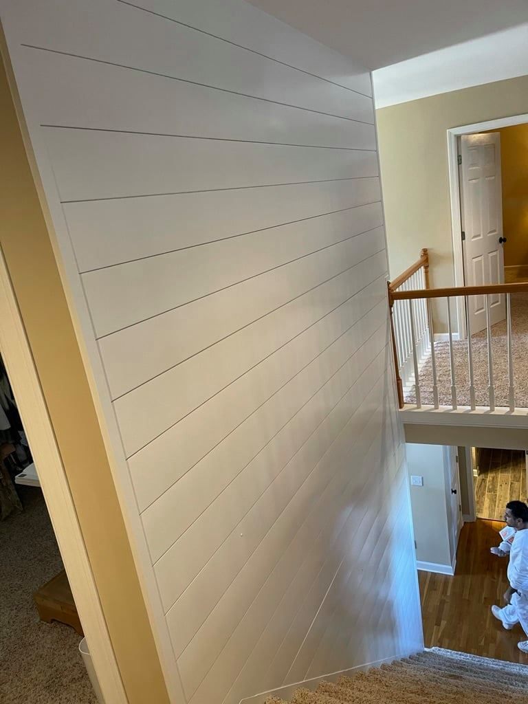 White stair wall with diagonal dotted markings, viewed from an upstairs landing in a home