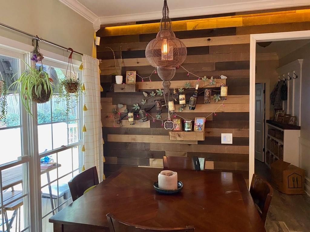 Rustic dining room with wooden table, hanging light, and plant-filled window nook