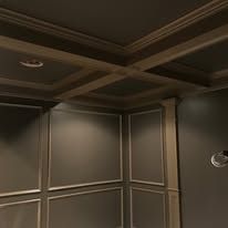 Dark paneled interior corner with coffered ceiling and wall trim in muted gray tones