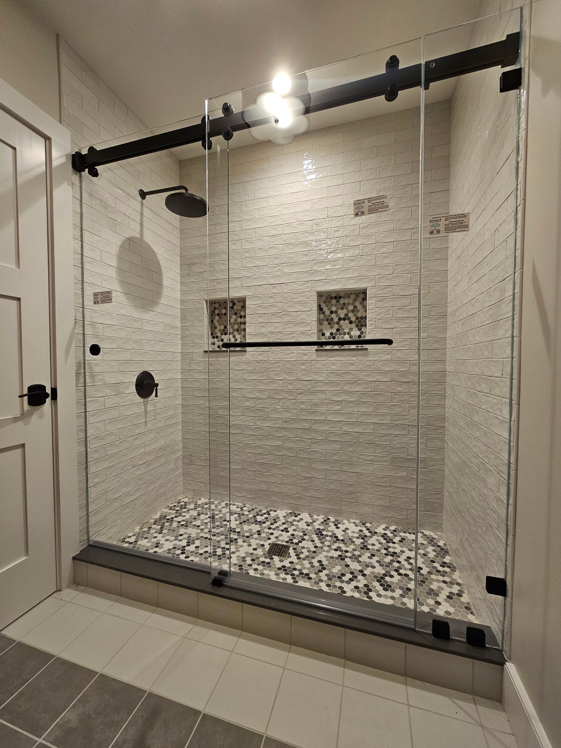 Glass shower enclosure with sliding door and pebble floor.