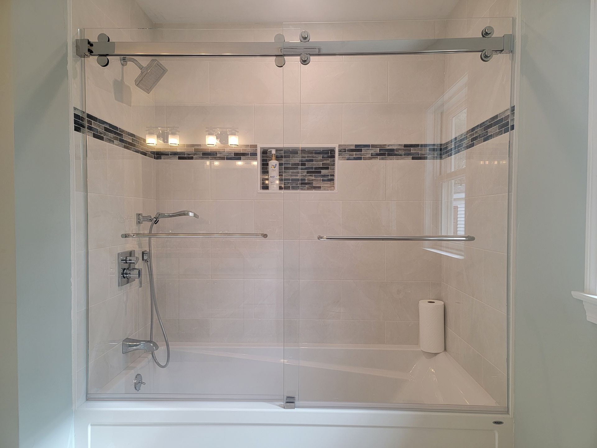 Shower with sliding glass doors, stainless steel hardware, and white tile.
