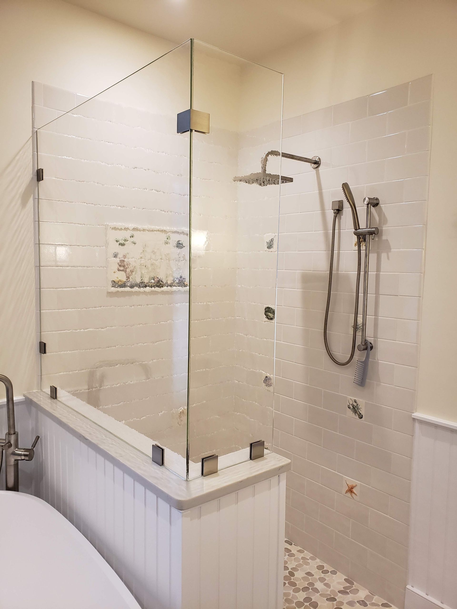 Glass shower enclosure with white tile walls and fixtures.