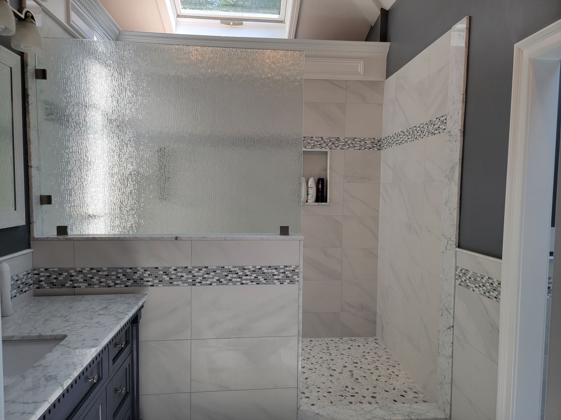 Bathroom with white tile, a glass shower, and a dark-colored vanity.