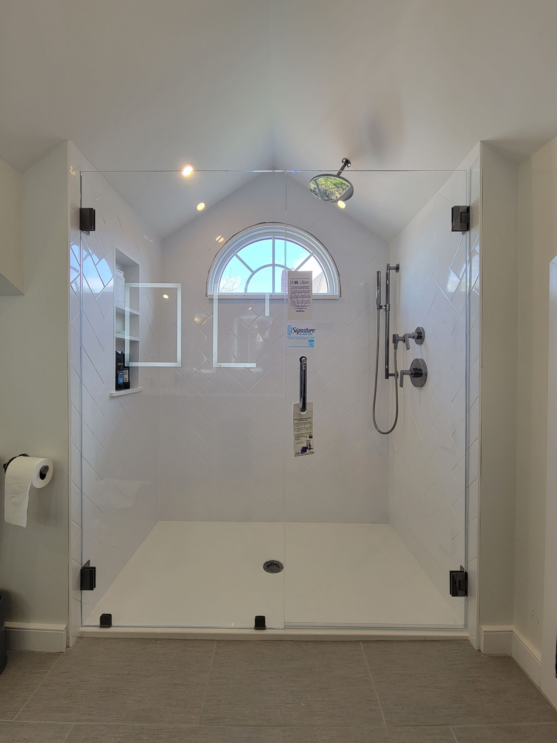 White tile shower with glass doors and a half-moon window. Dark hinges.