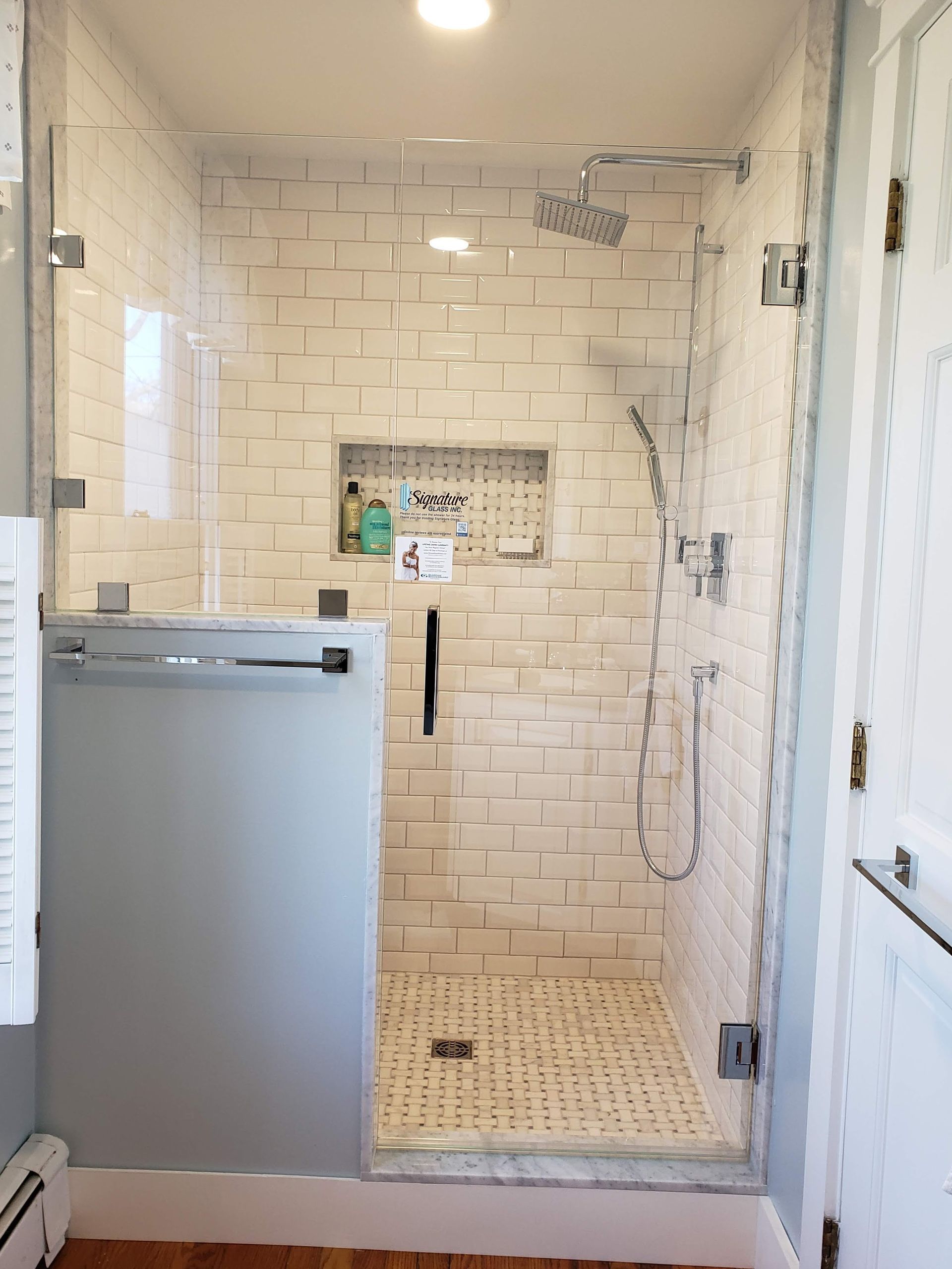 A modern, tiled shower with glass doors and a built-in shelf.