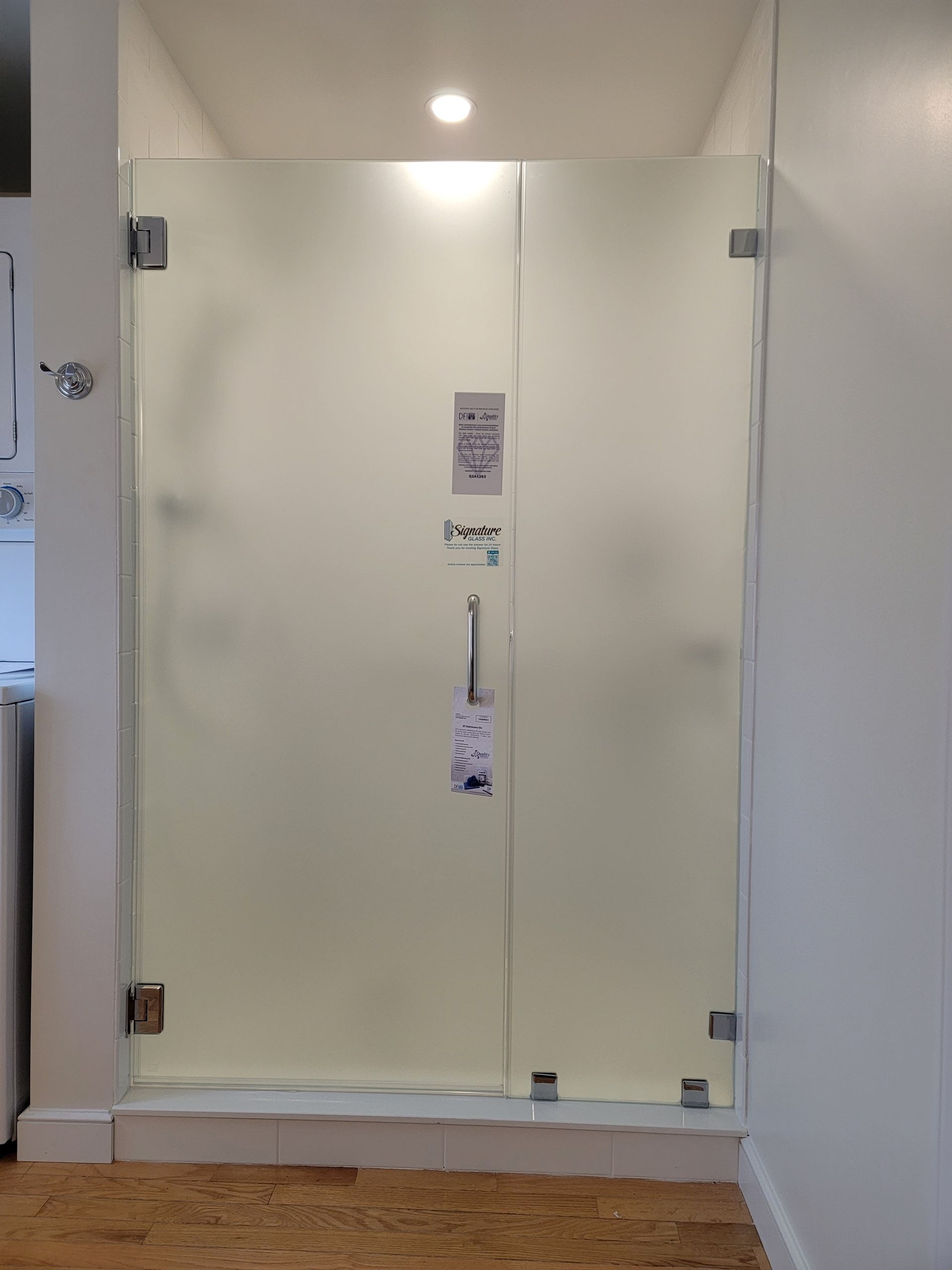 Frosted glass shower door with silver hardware in a bathroom.