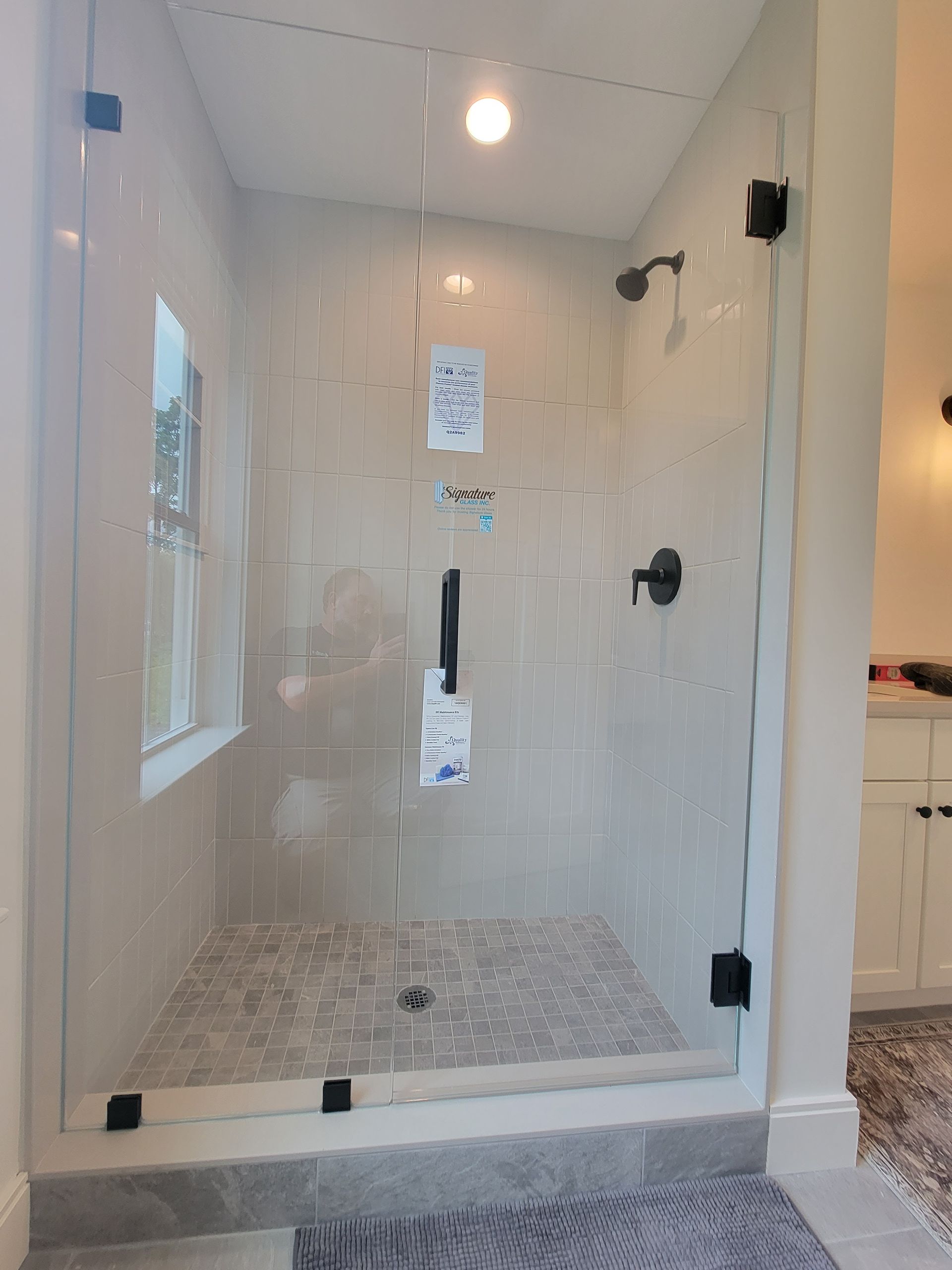 Glass shower enclosure in a bathroom with patterned tile flooring and black hardware.
