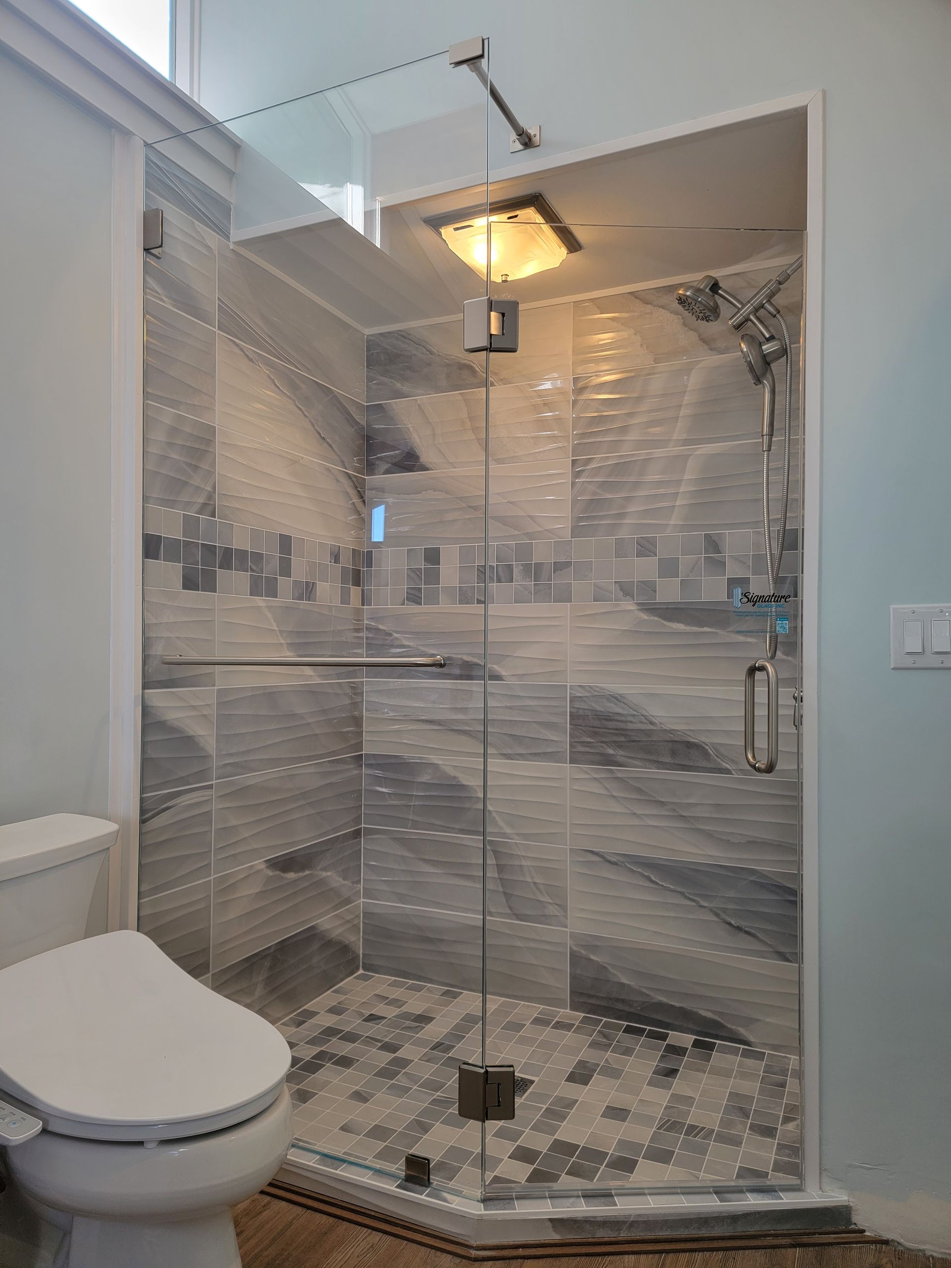 Modern bathroom with glass shower, patterned tiles, and toilet.