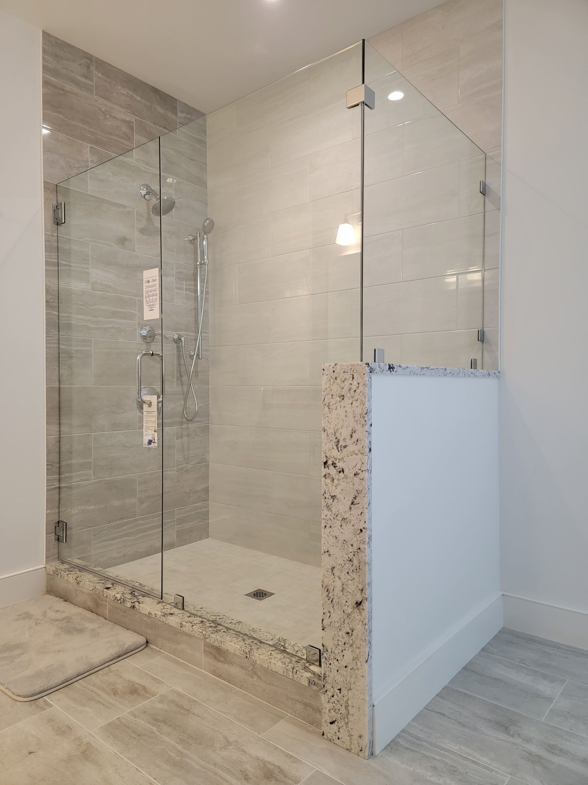 Glass shower enclosure with gray tile walls and stone base.