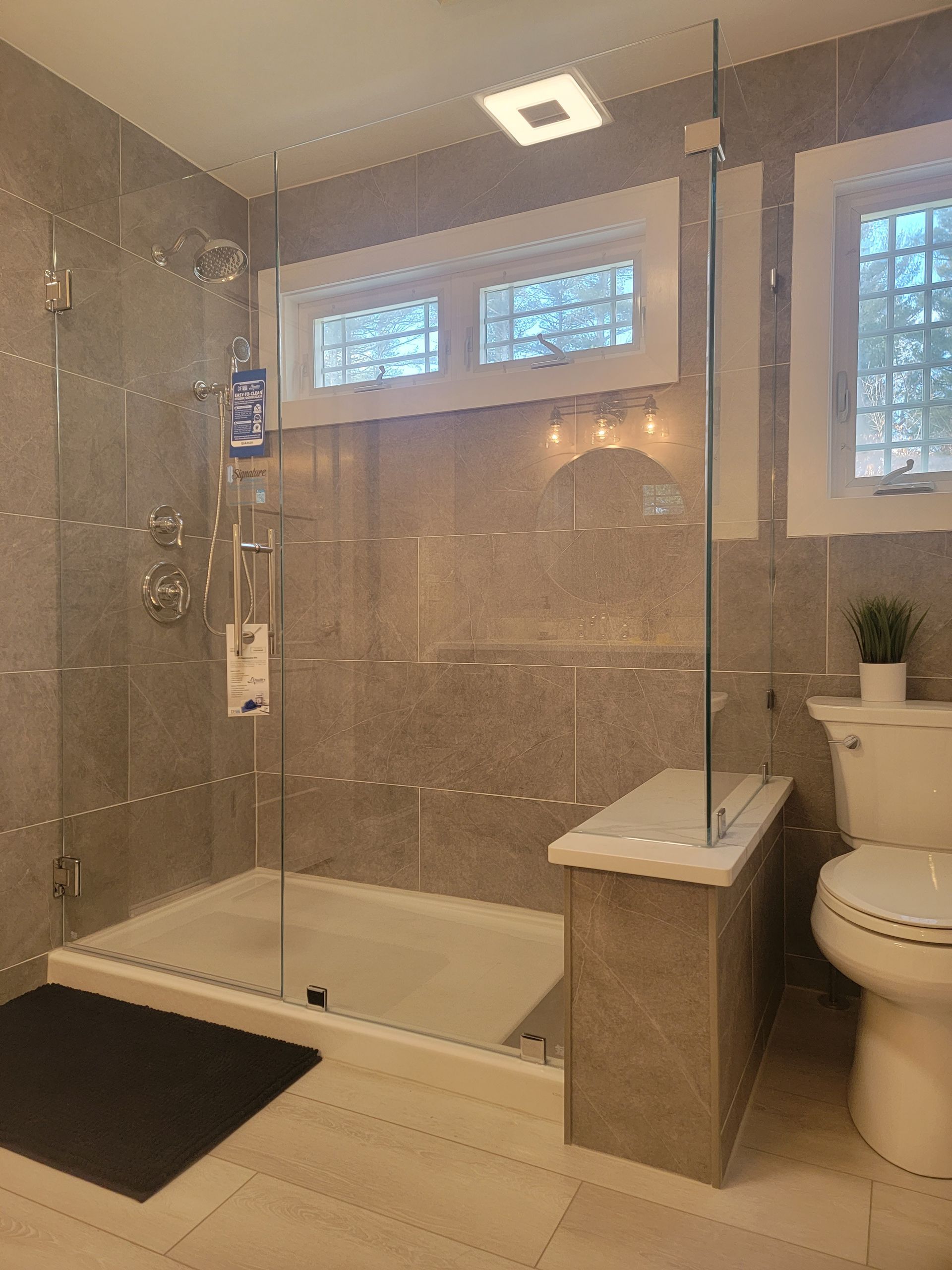 Modern bathroom with glass shower, gray tiles, and a toilet.
