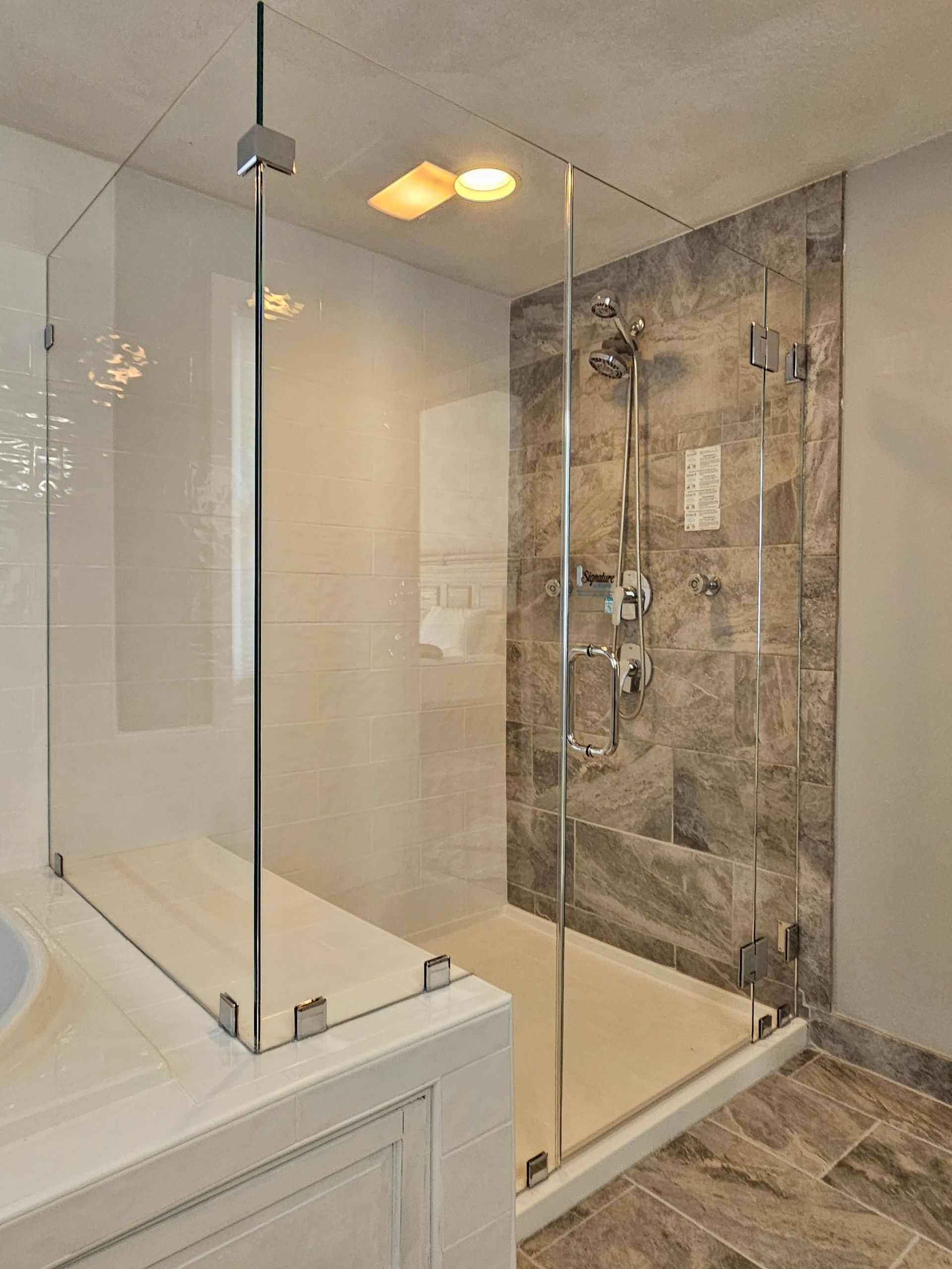 Modern glass shower enclosure with gray tile wall and chrome fixtures.
