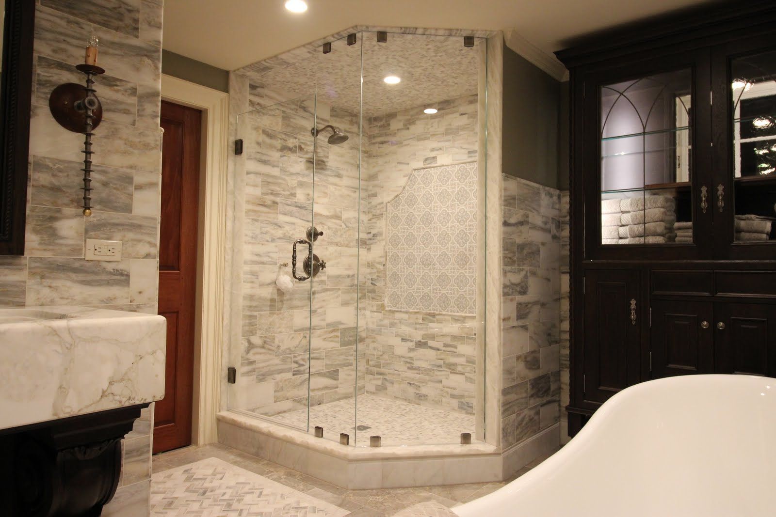 Luxurious bathroom with a glass-enclosed shower, marble tiles, and dark cabinetry.