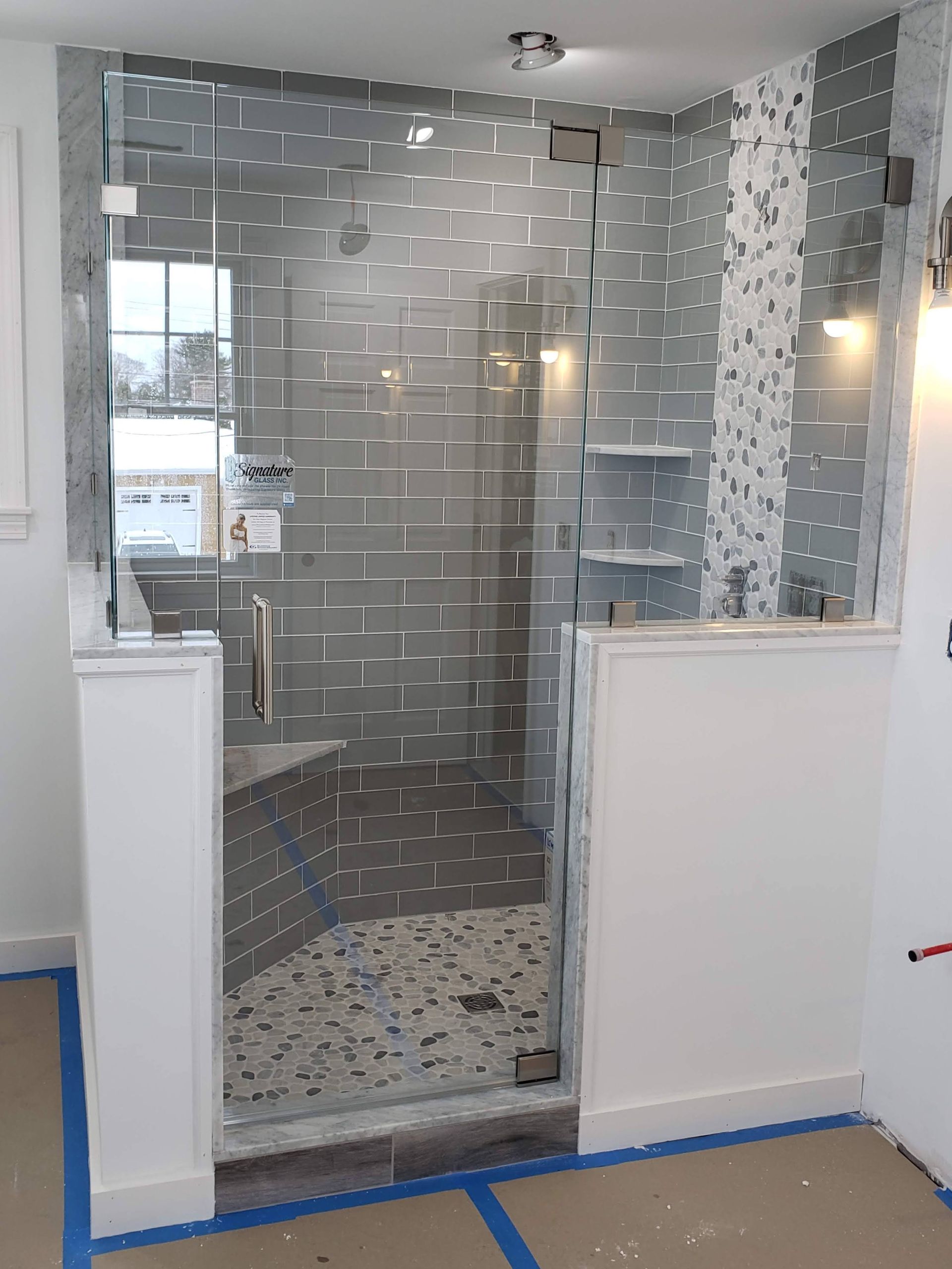 Glass shower enclosure with gray tiled walls and a white-trimmed entrance.