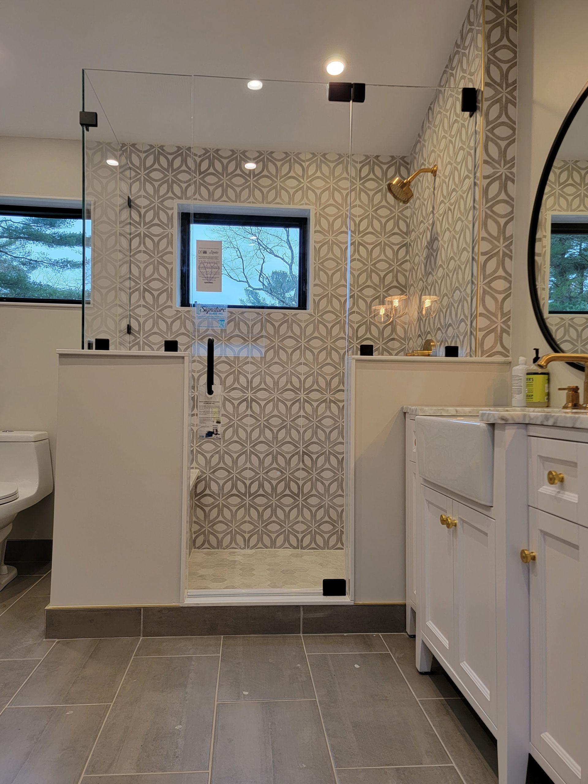 Bathroom with tile shower, glass door, white vanity, and gray floor.