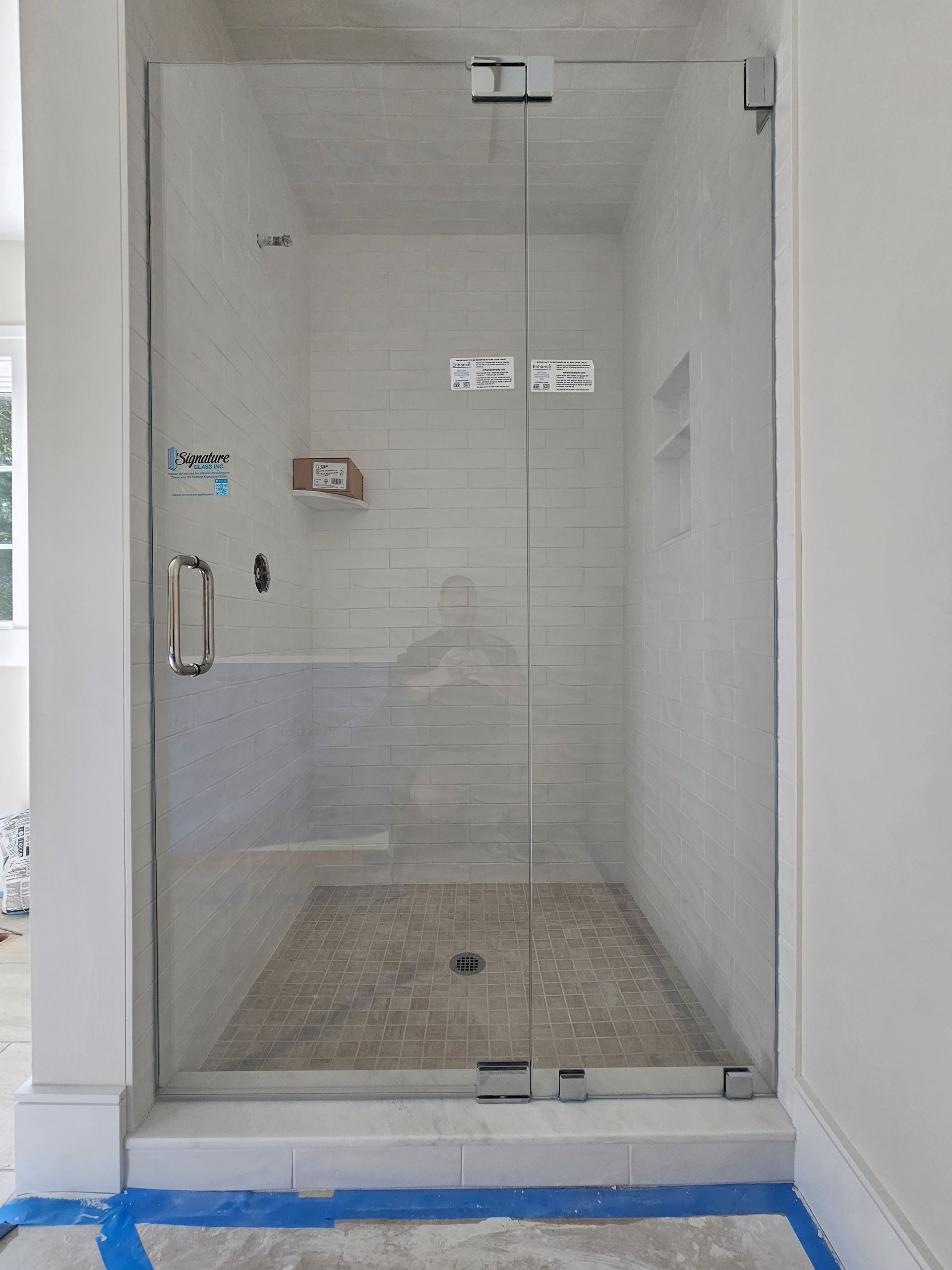 Glass shower enclosure with gray tiled interior.