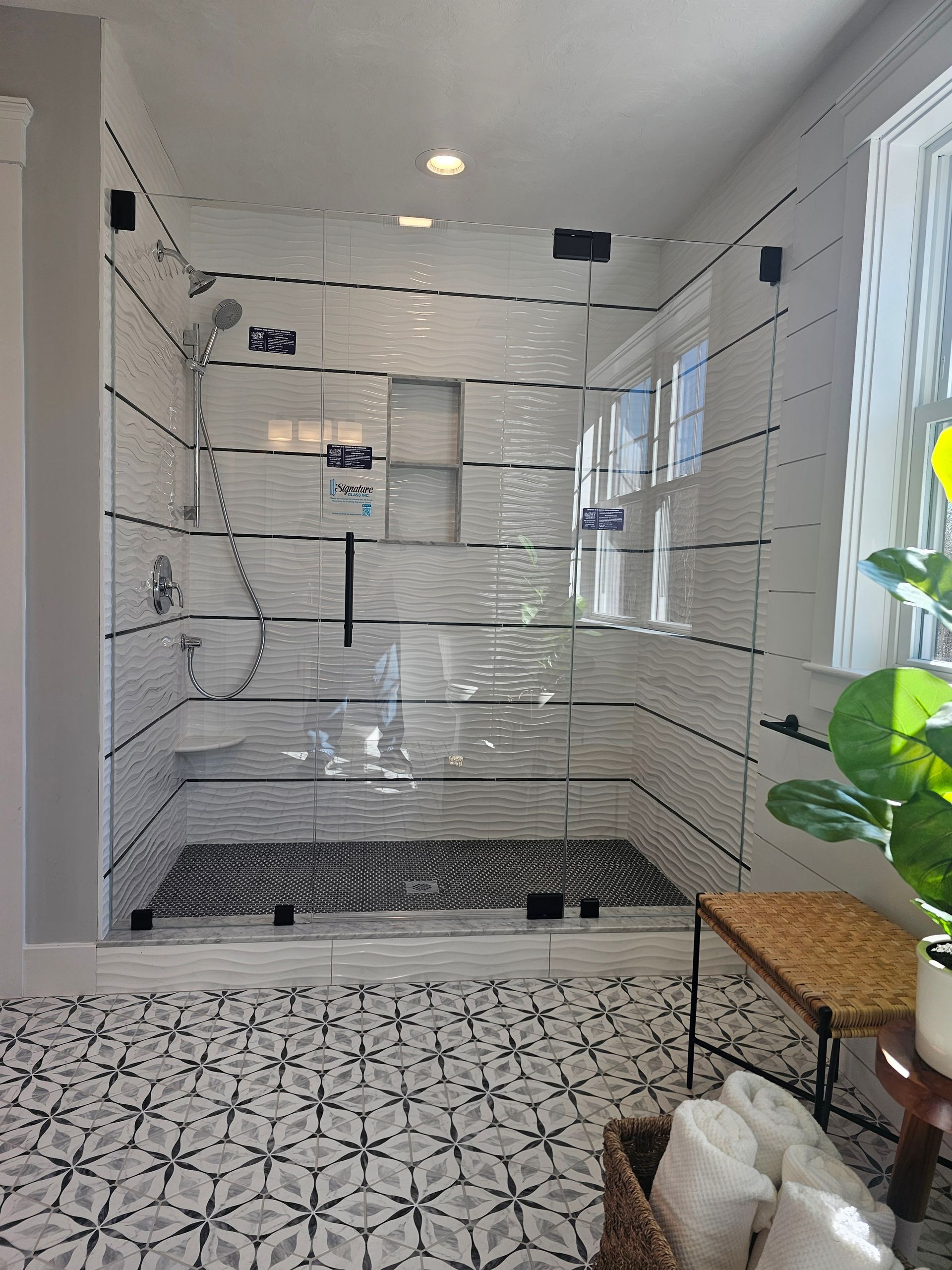 Modern bathroom with a glass shower enclosure and patterned floor tiles.