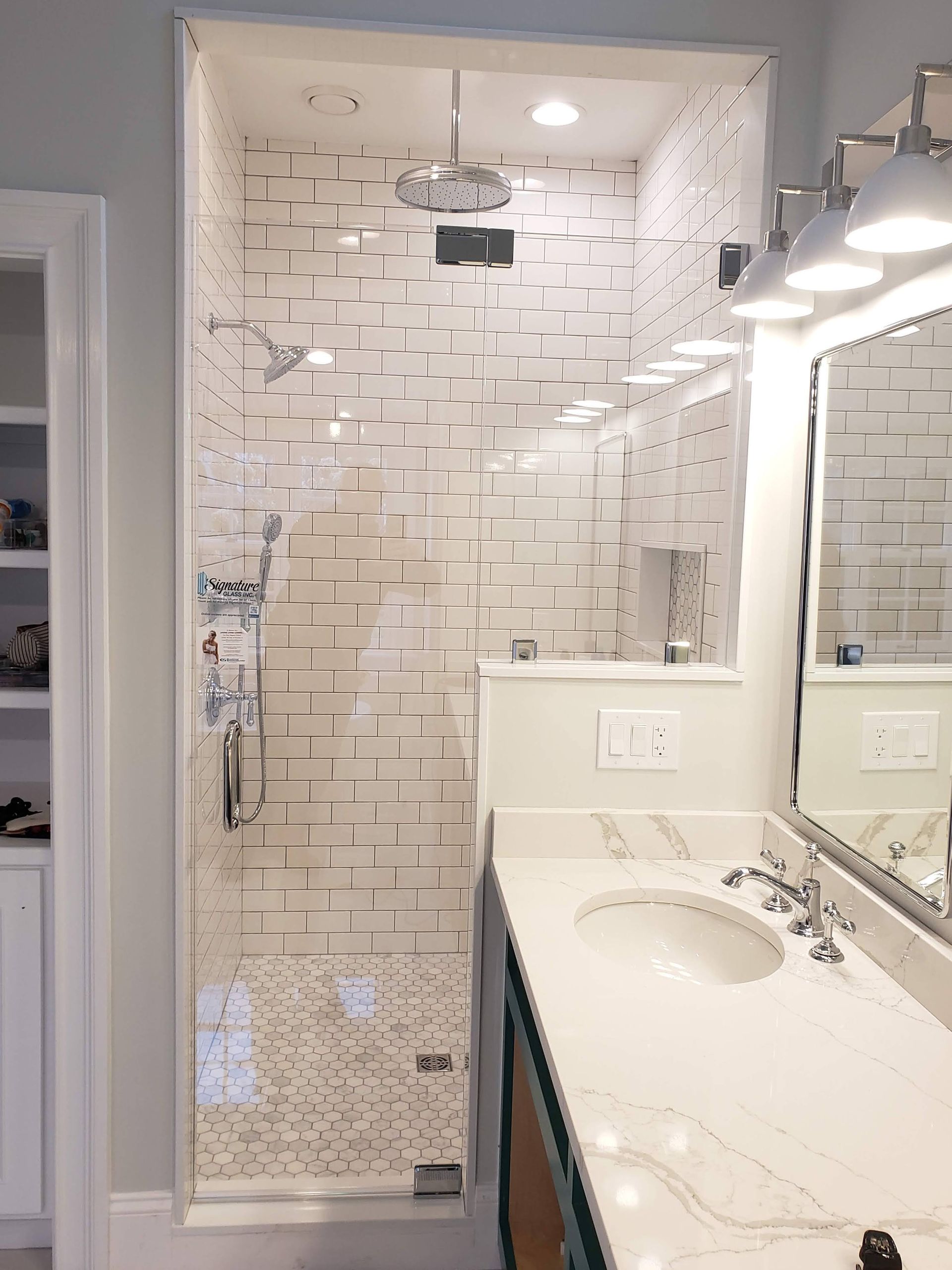 Bathroom with a glass shower, white subway tile, a sink, and a vanity.