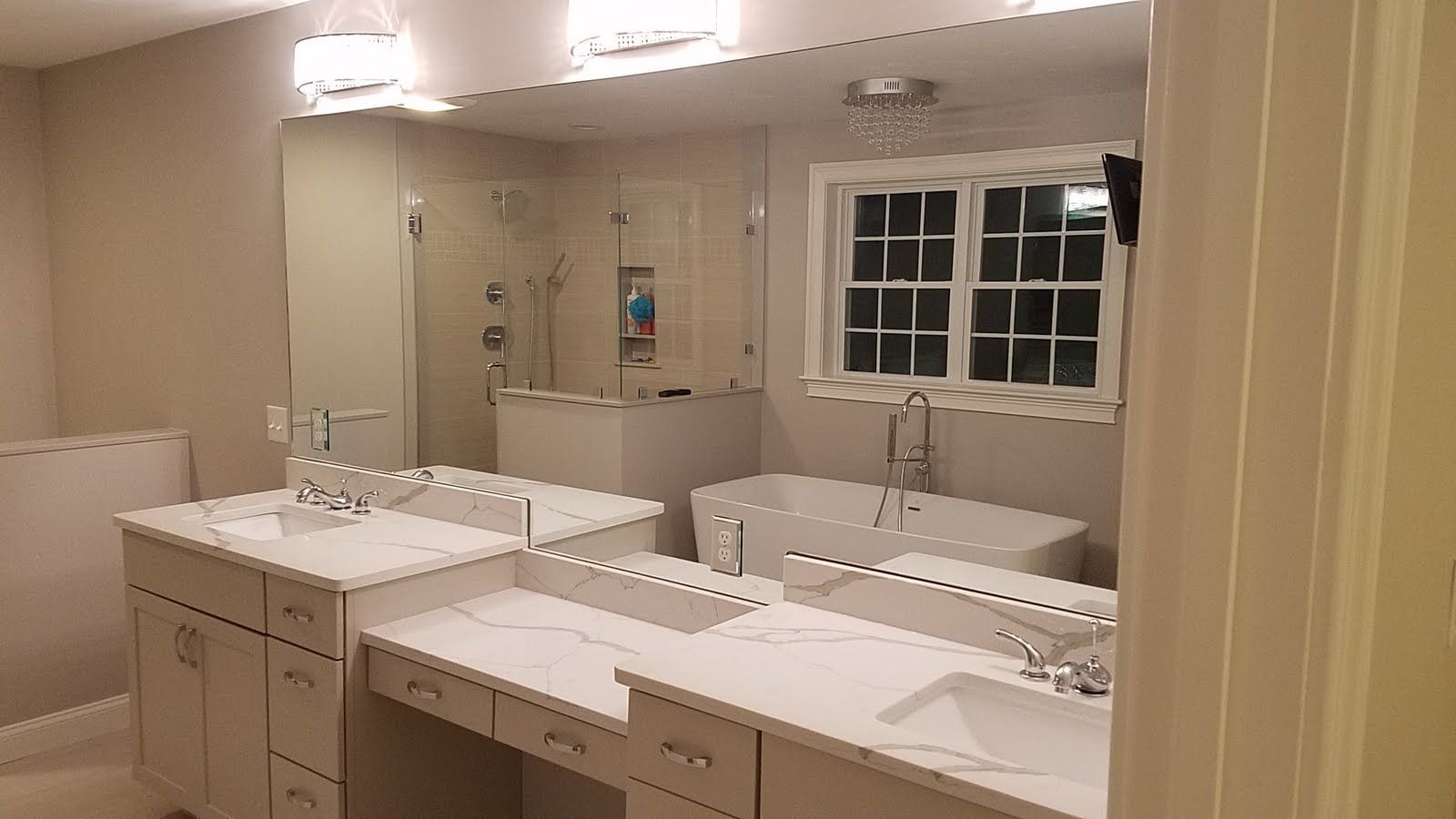 Modern bathroom with white cabinets, large mirror, soaking tub, and shower.