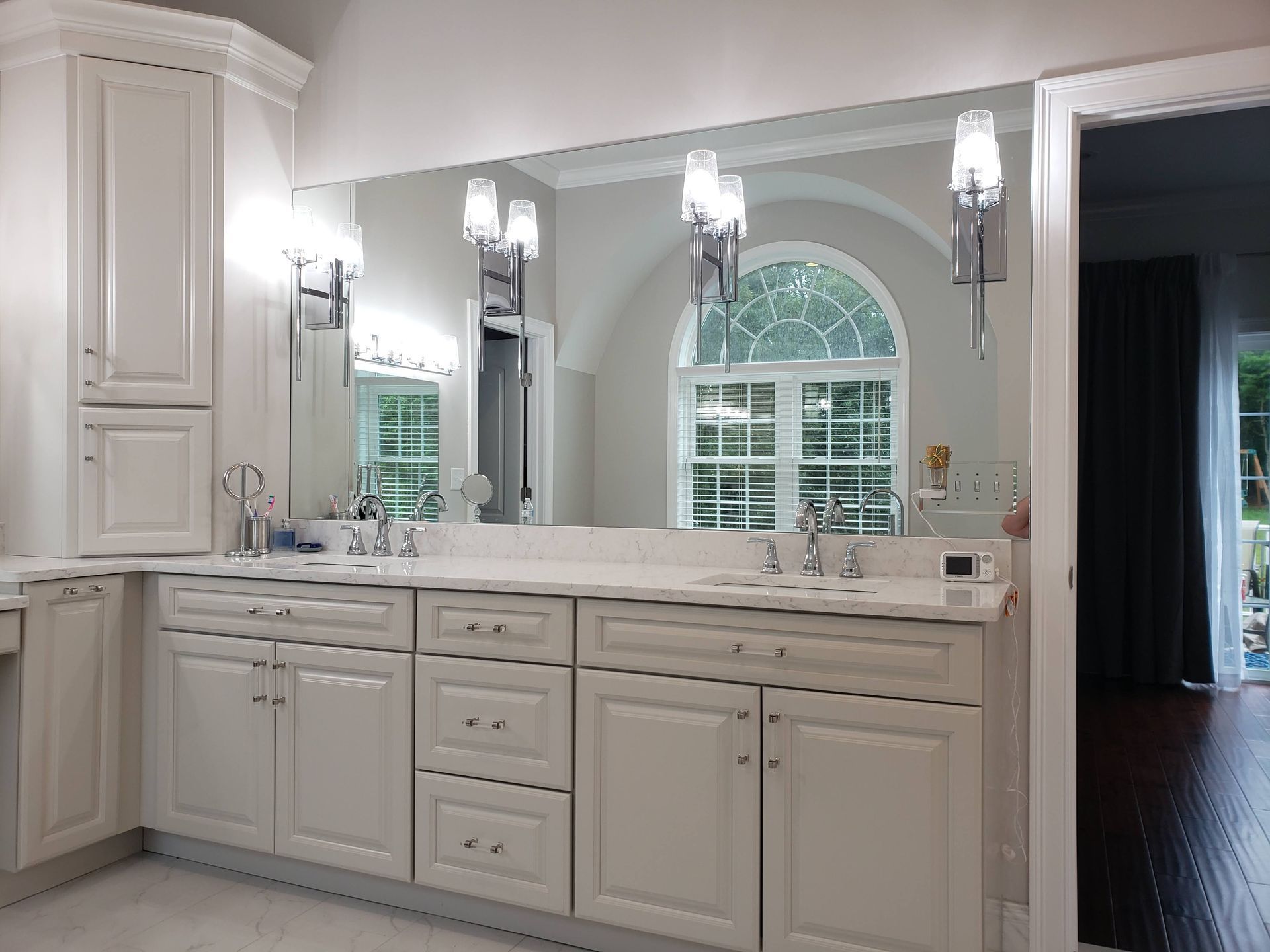 White bathroom vanity with mirrors, lights, and a window.