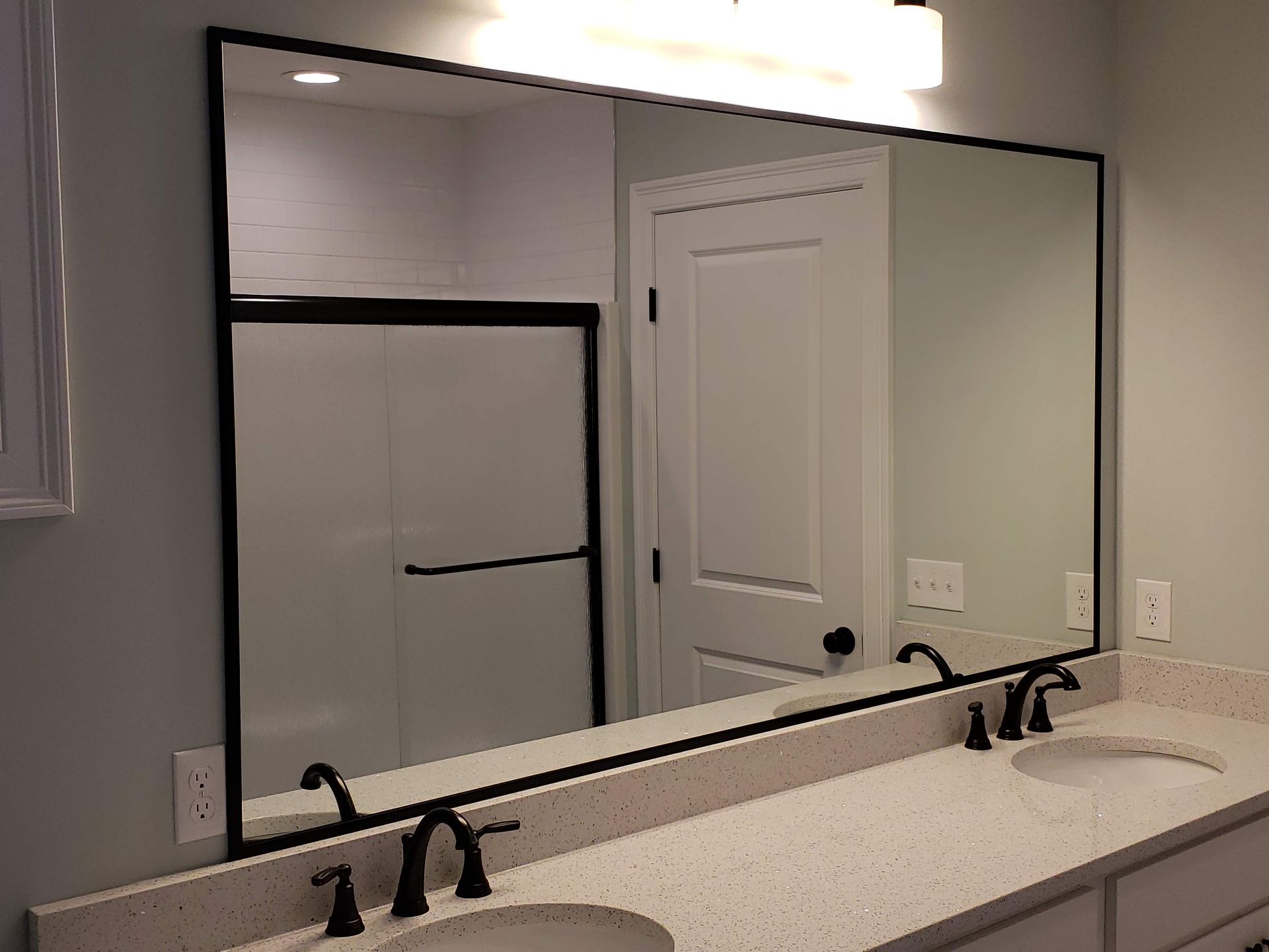 Bathroom with large framed mirror over a double sink vanity. Black fixtures and trim.