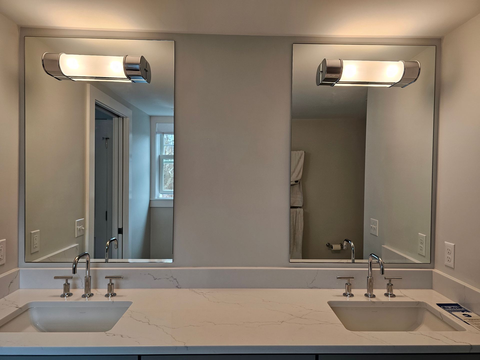 Two bathroom sinks with mirrors and light fixtures.