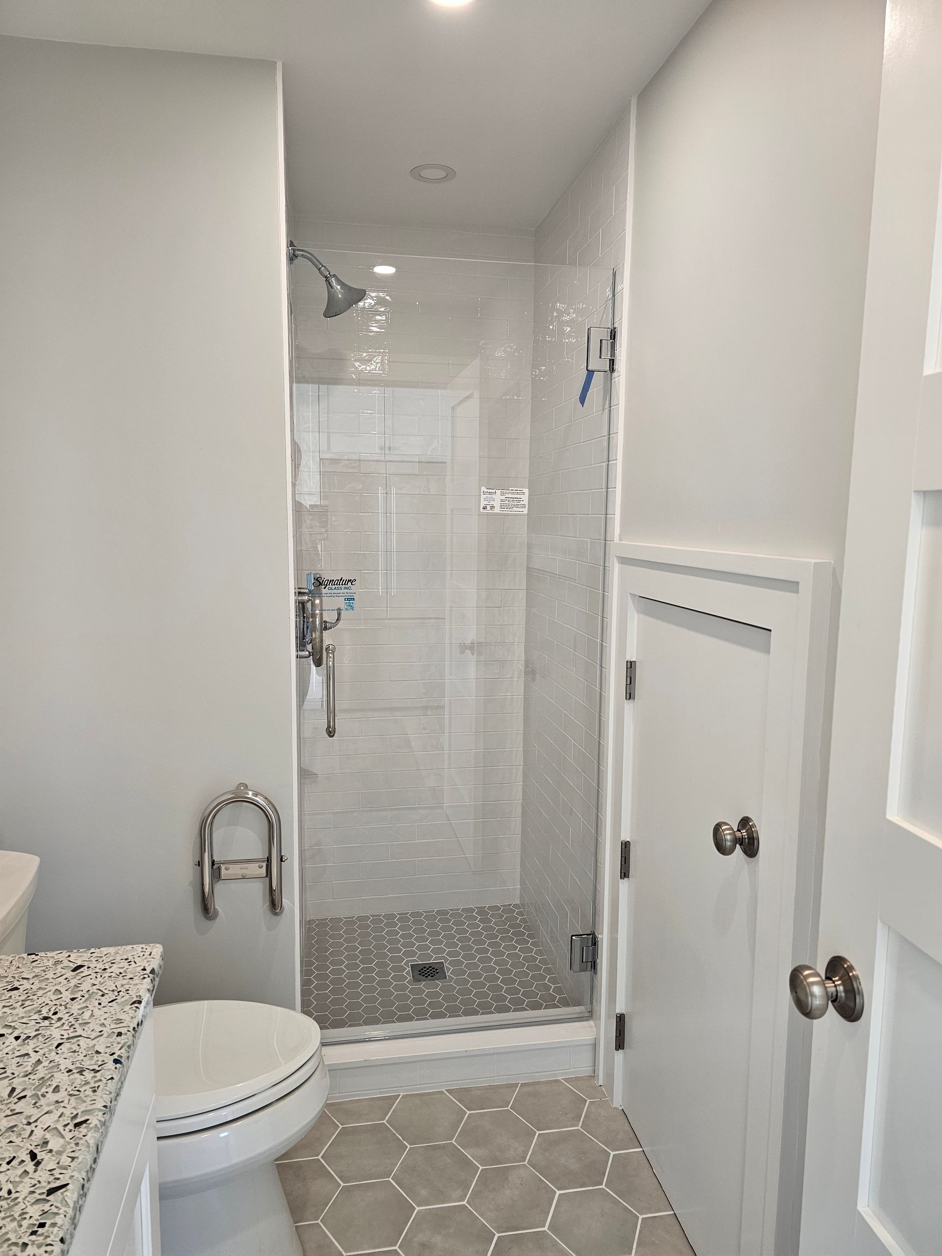 Bathroom with a glass shower, white walls, and a toilet.