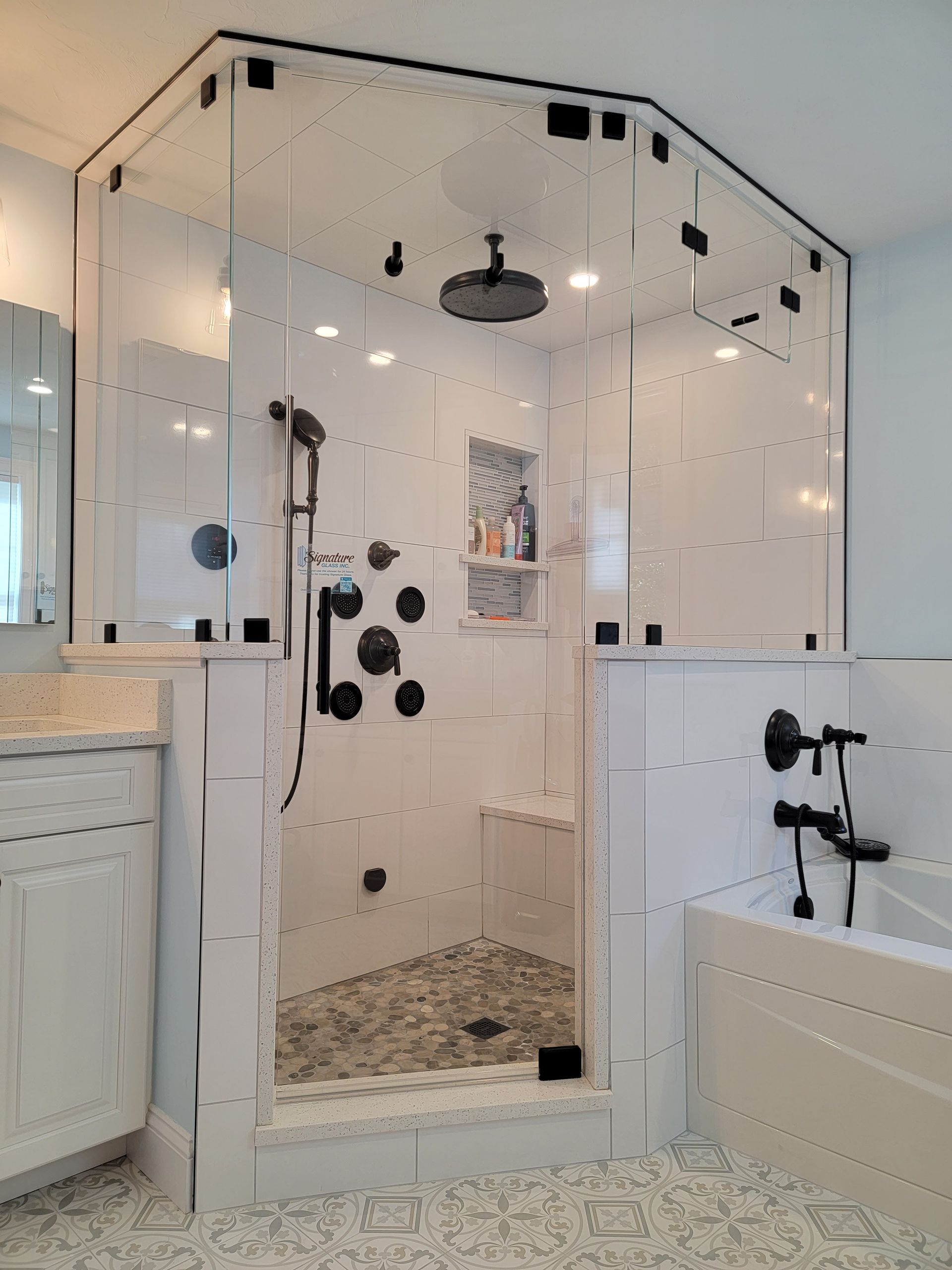 Modern white tiled shower with glass enclosure and black fixtures.