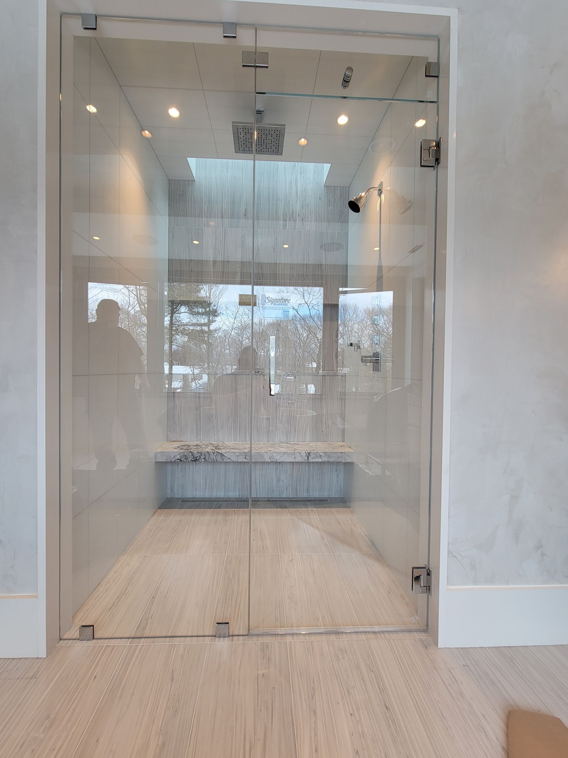Double glass doors leading into a room with a light wood floor and a skylight.