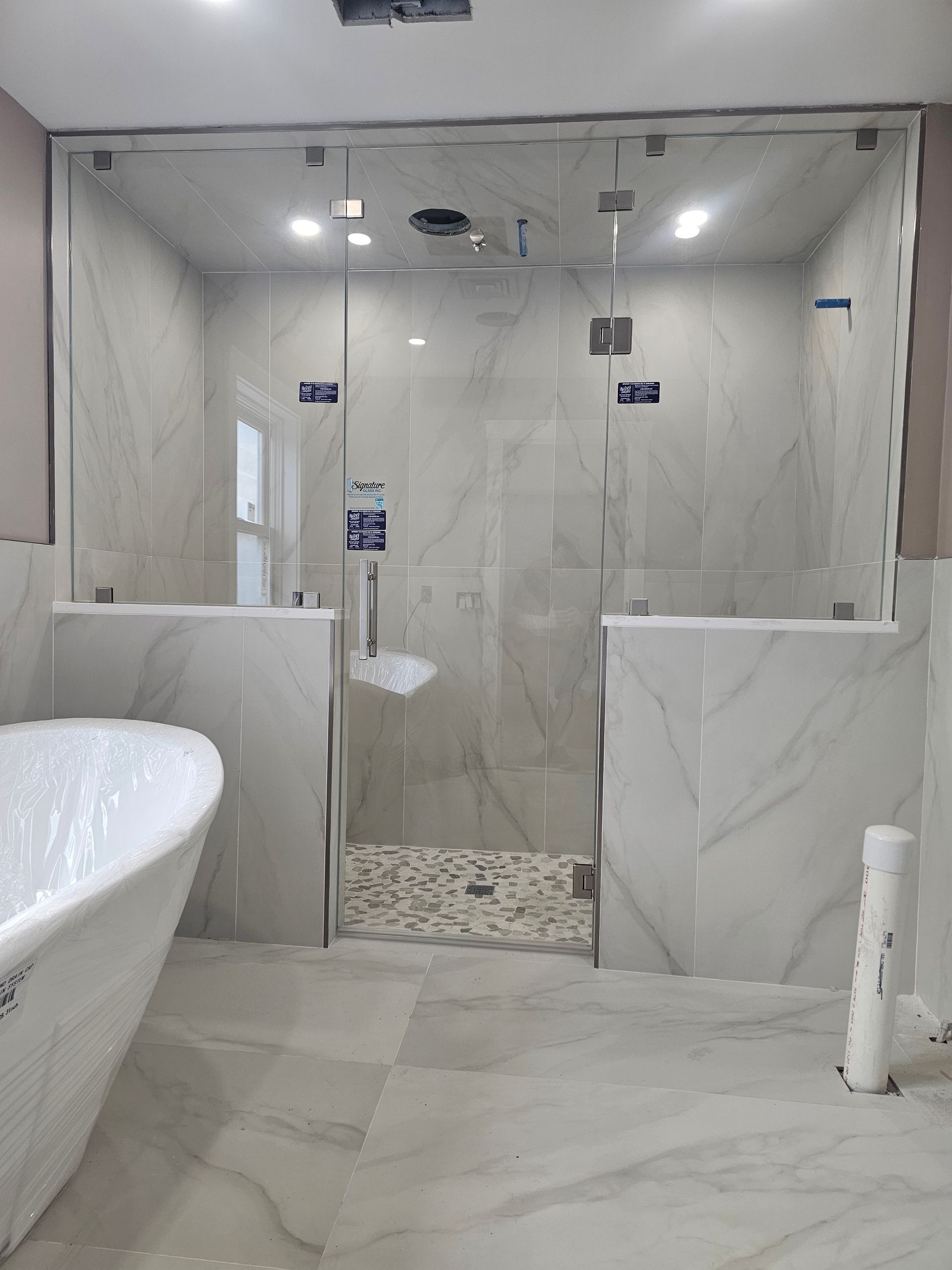 Bathroom with marble tile, glass shower enclosure, and a bathtub.